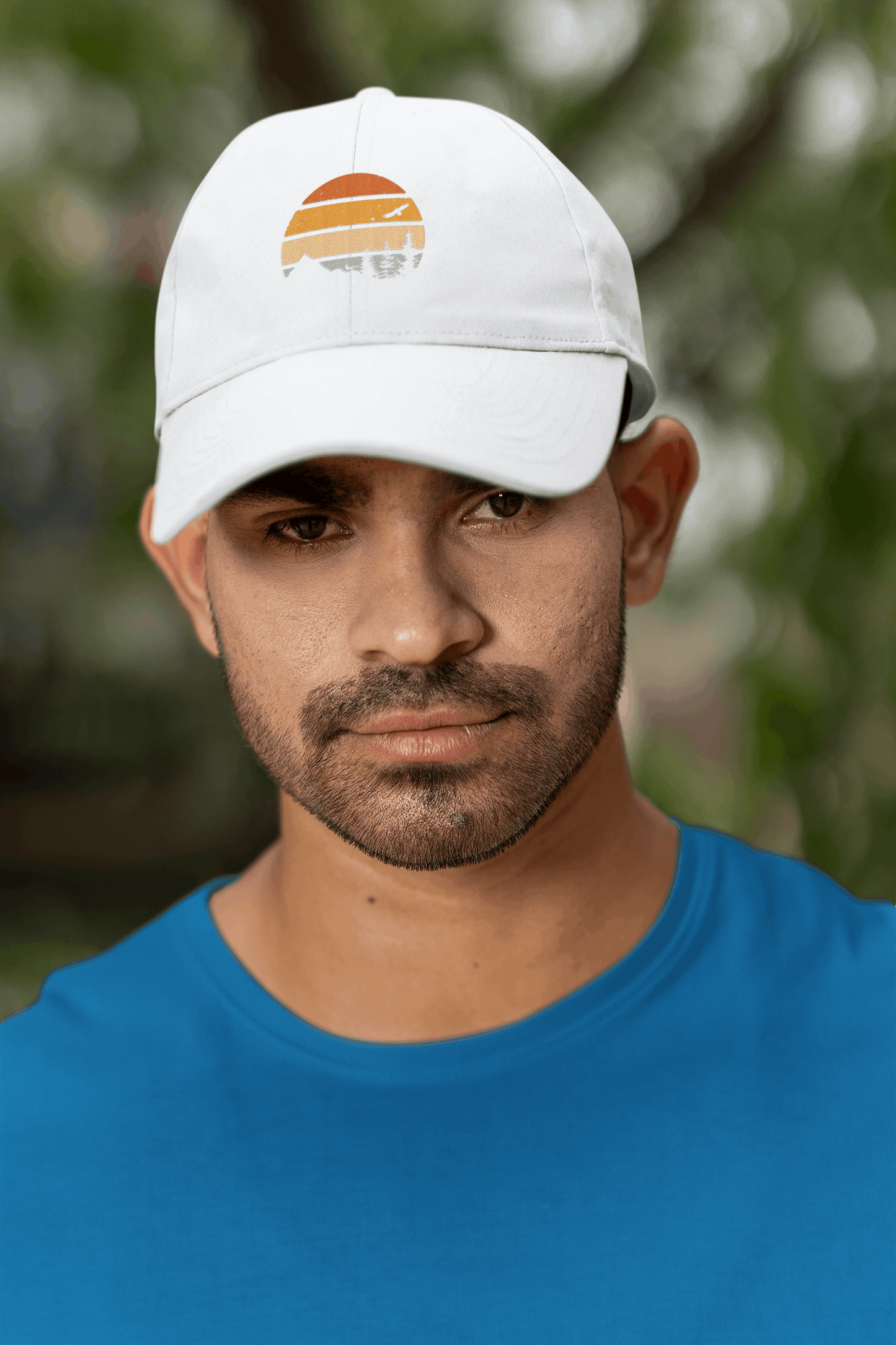 White Madeira Vintage Cap with a mountain logo, worn by a man in a blue shirt. A clean and stylish adventure-inspired accessory.