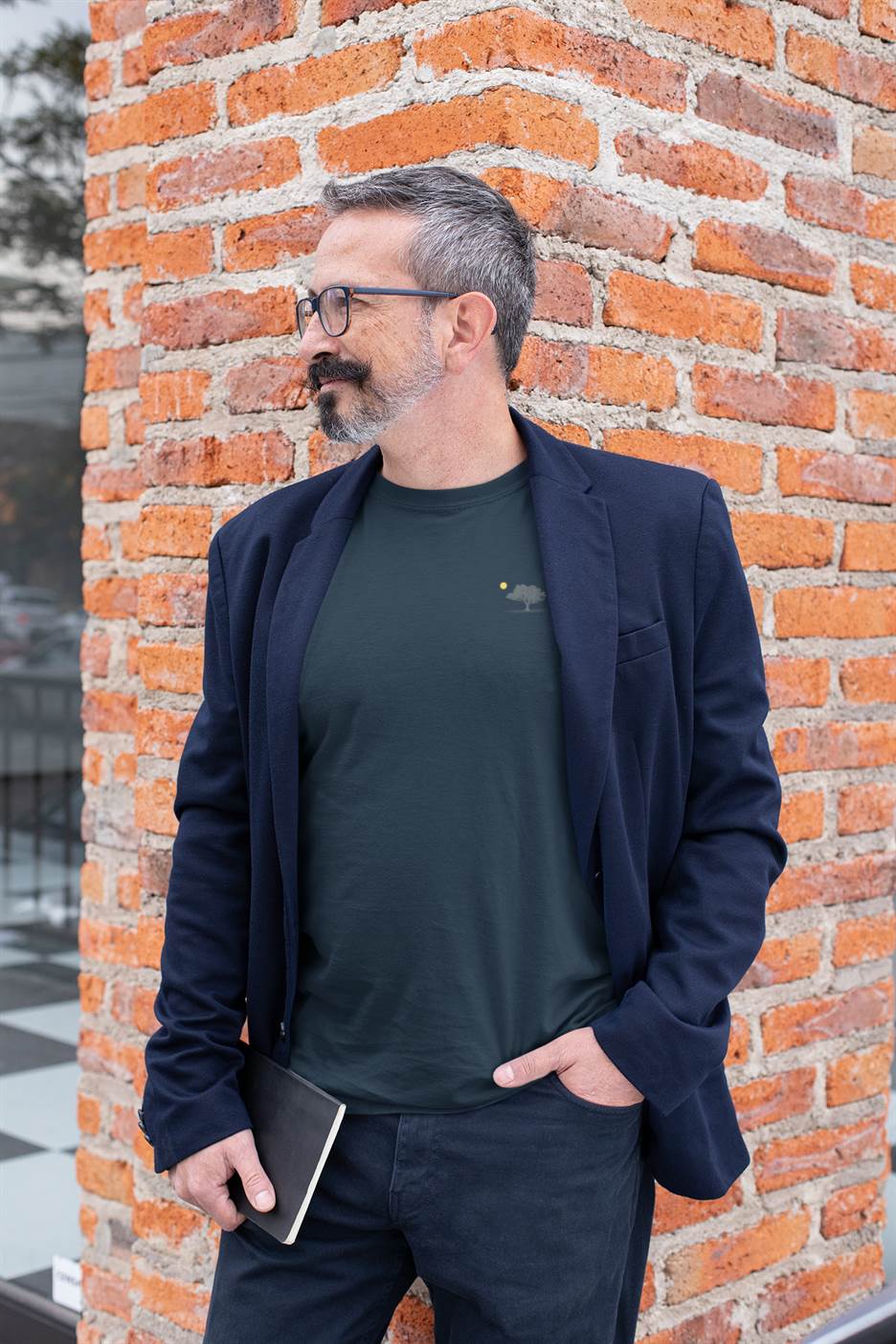 Man in a navy blue blazer wearing a dark organic T-shirt with a minimalist oak tree and sunset design. A blend of casual and sophisticated style.