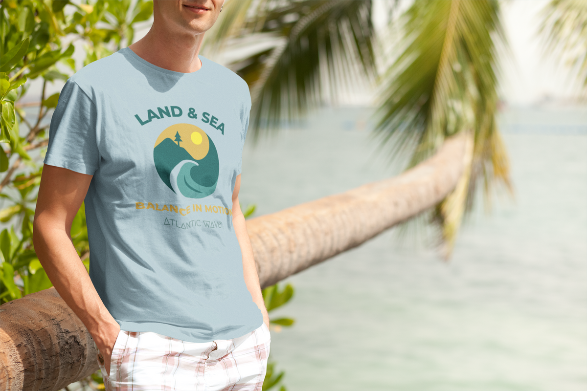 Light blue organic cotton t-shirt with colorful Land & Sea graphic, worn outdoors by man near palm tree, Portugal beach.