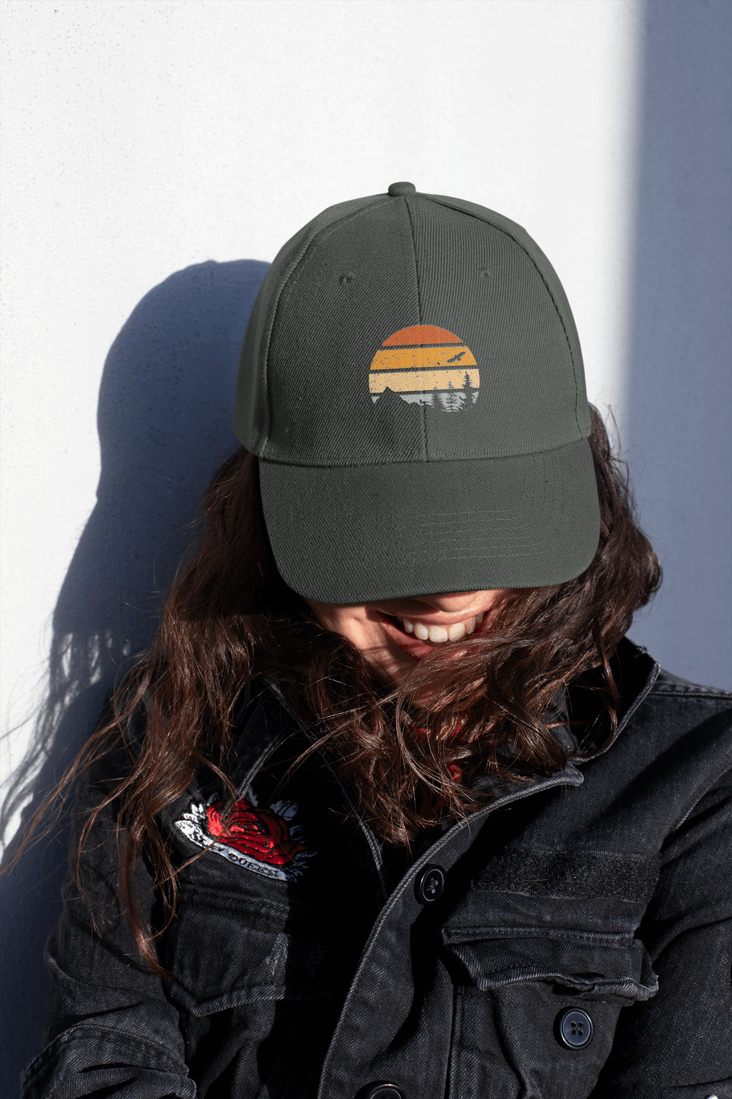 Portugal's Madeira Vintage Cap in dark green with a mountain logo, worn by a smiling woman in a black jacket. Adventure-style headwear for outdoor enthusiasts.