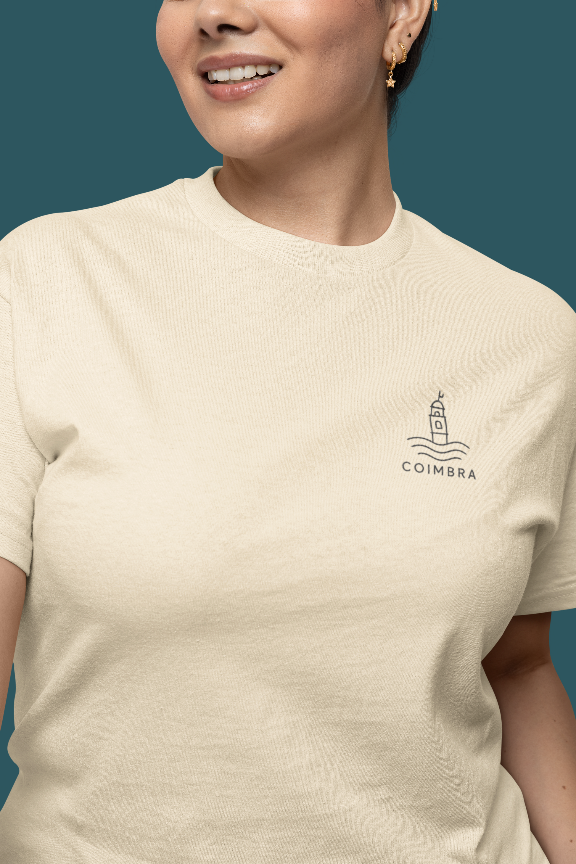 Person wearing a beige t-shirt with Coimbra logo on a teal background