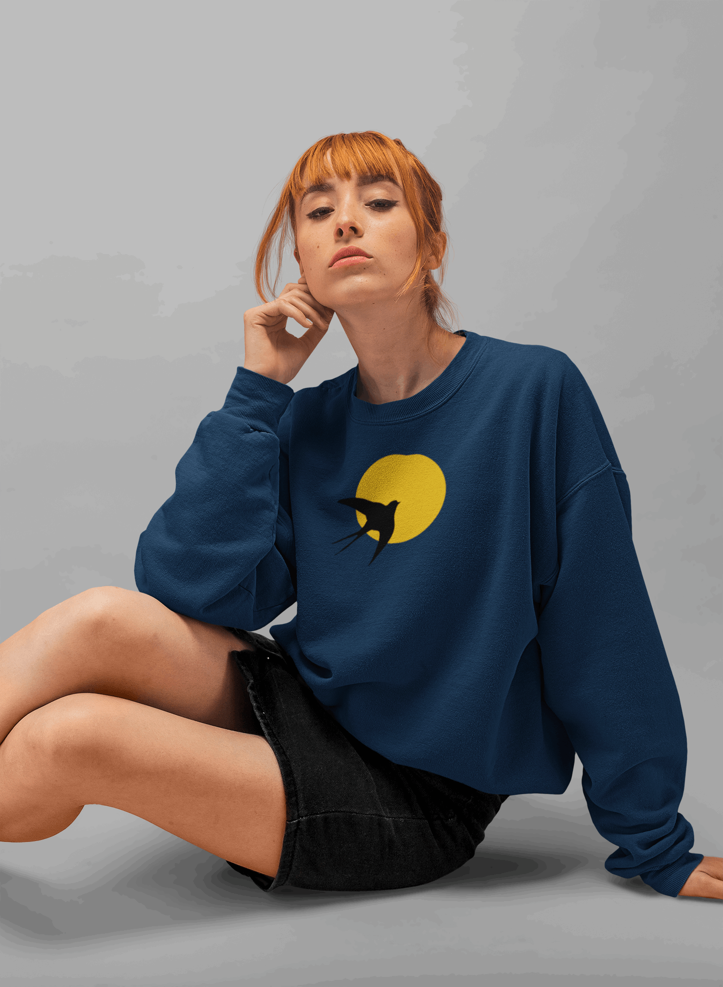 Navy blue unisex organic sweater showcasing a minimal Andorinha swallow logo with a yellow sun, crafted from organic cotton for sustainable fashion.