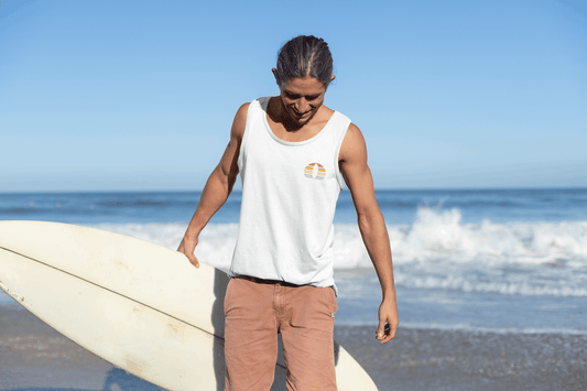 White Nazaré Surf Minimal tank top with a retro surf logo, worn by a surfer. A lightweight organic cotton tank designed for coastal adventures.