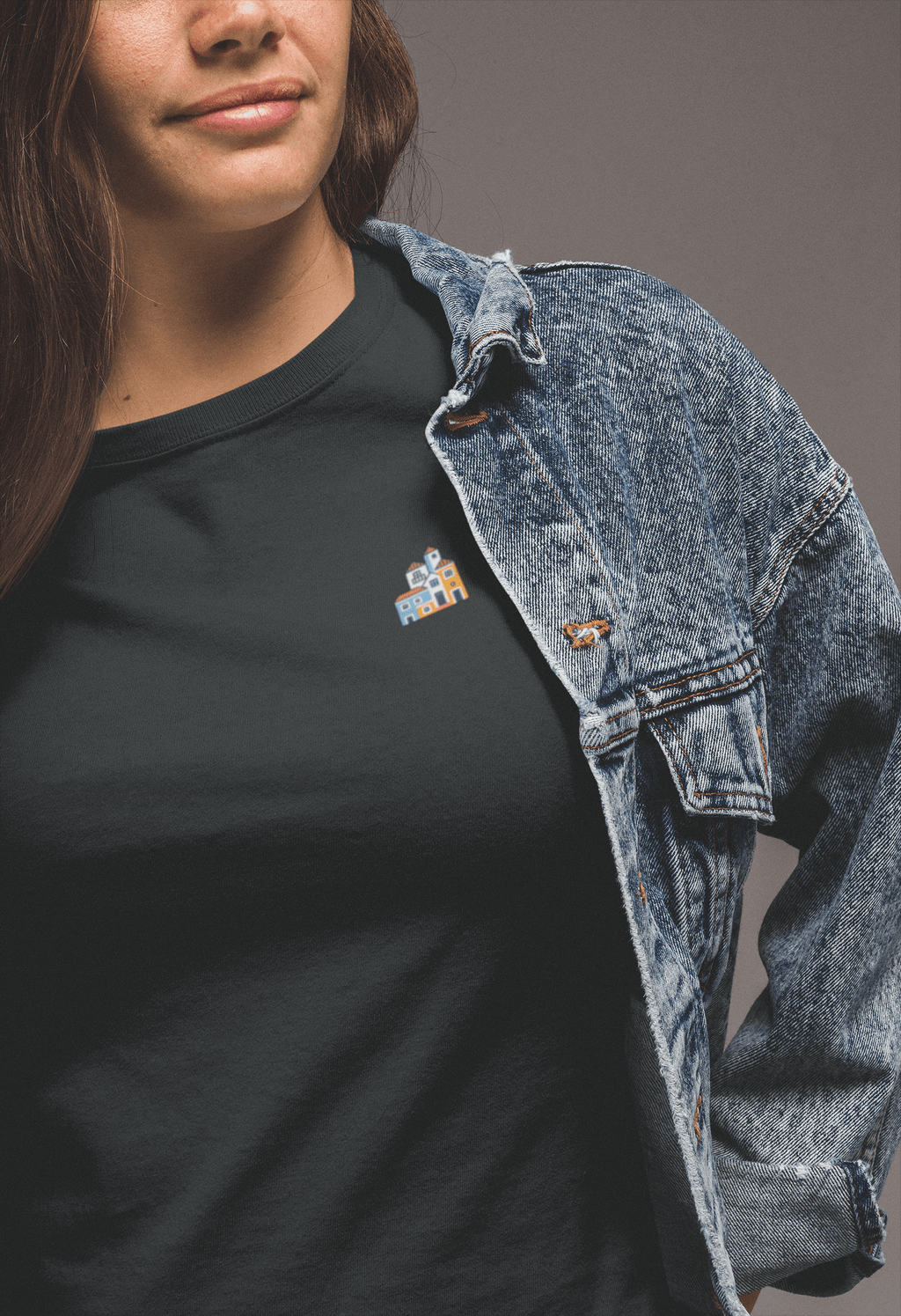 Woman in a black Minimal Alfama Houses Unisex T-Shirt with a denim jacket, featuring a small Lisbon-inspired house design on organic cotton.