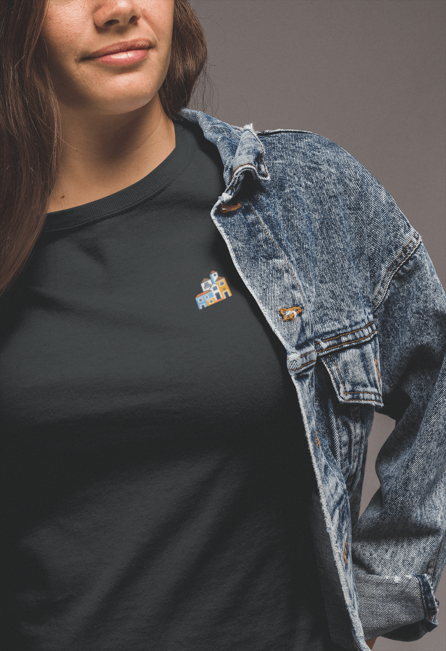 Woman in a black Minimal Alfama Houses Unisex T-Shirt with a denim jacket, featuring a small Lisbon-inspired house design on organic cotton.