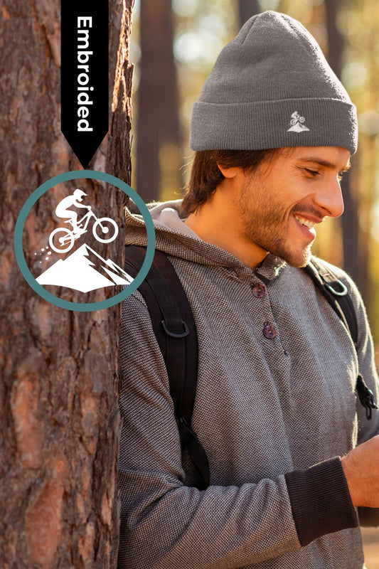 Gray Madeira Beanie with embroidered mountain bike logo, worn by a man in a forest. Stylish and warm, perfect for outdoor adventures.