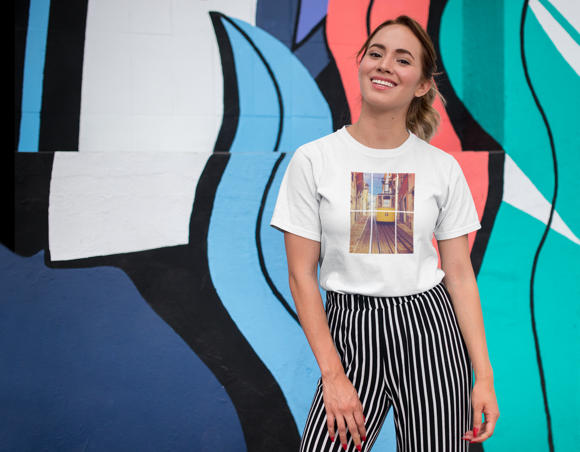 Smiling woman wearing a Lisbon Tram T-shirt against a colorful mural. Organic cotton and eco-friendly fabric make it a perfect sustainable fashion choice.