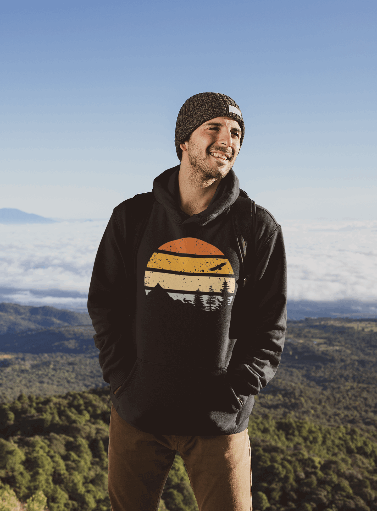 Black organic cotton hoodie featuring a vintage sunset and mountain design, worn by a man enjoying a scenic mountain view.