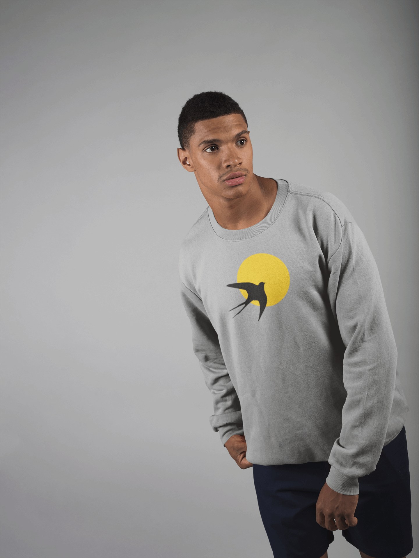 Light gray unisex organic sweater featuring a minimal Andorinha swallow logo with a yellow sun, crafted from sustainable organic cotton for comfort.