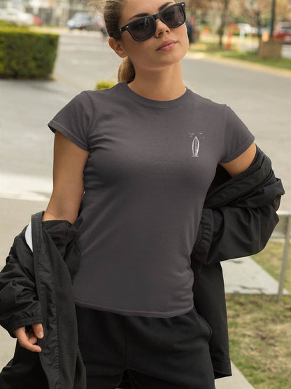 Dark gray Ericeira Surf Organic T-Shirt for women, featuring a minimalist surfboard design, styled with a black jacket and sunglasses for a sporty look.
