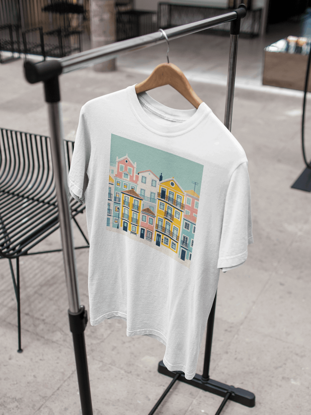White organic cotton T-shirt with Lisbon Alfama houses design hanging on a rack. A sustainable and stylish unisex wardrobe essential.