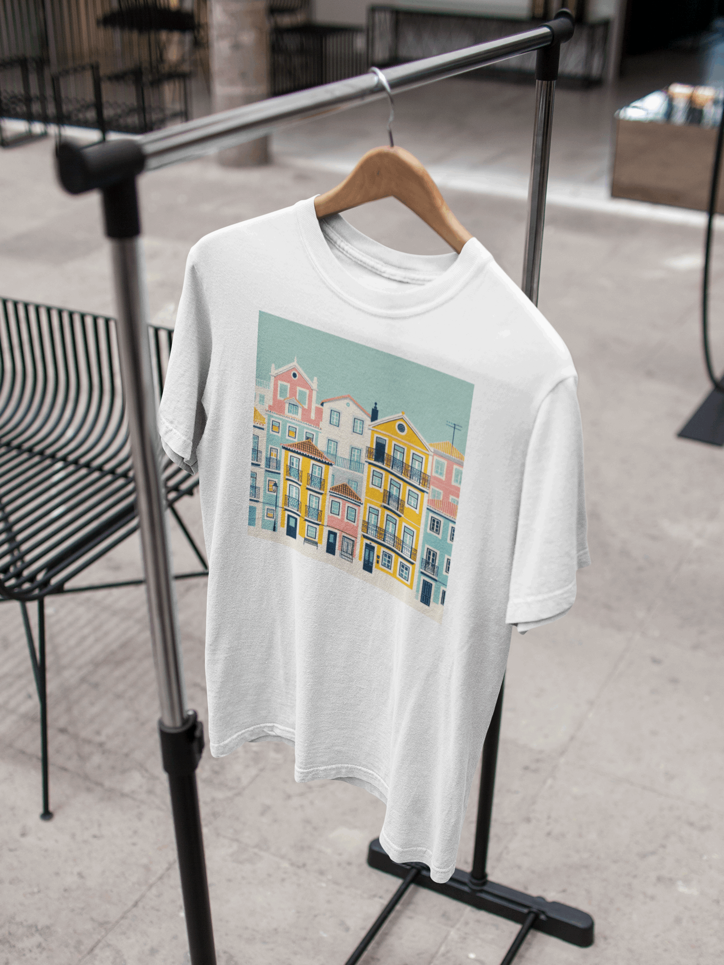 White organic cotton T-shirt with Lisbon Alfama houses design hanging on a rack. A sustainable and stylish unisex wardrobe essential.