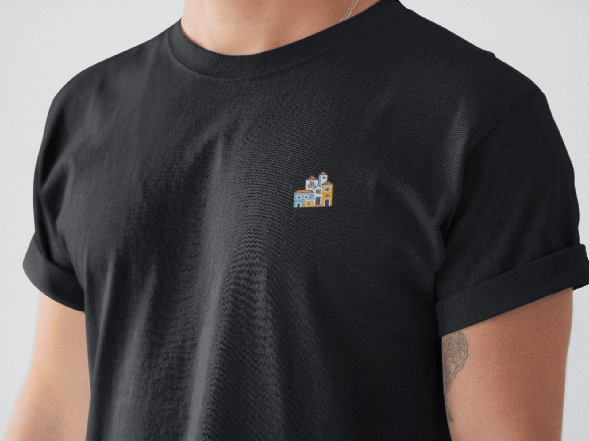 Close-up of a black Minimal Alfama Houses Unisex T-Shirt, featuring a small Lisbon-inspired house design on soft organic cotton fabric.