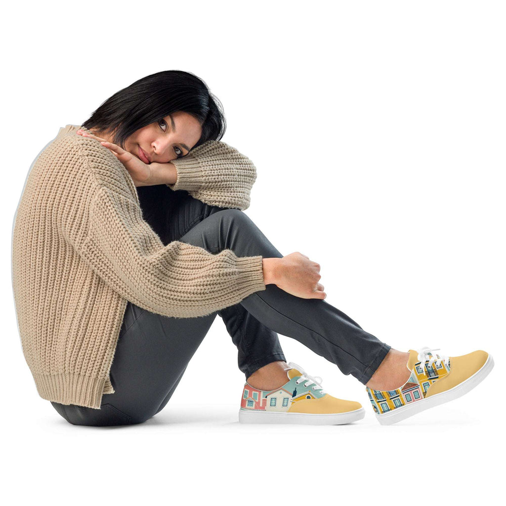 A woman sitting while wearing Lisbon's Alfama Sneakers, featuring a Lisbon-inspired yellow house pattern. A trendy and comfortable sneaker option.