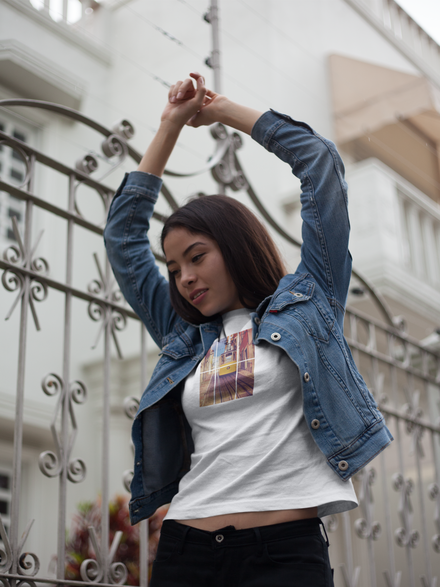 Woman in a Lisbon Tram T-shirt paired with a denim jacket, stretching outdoors. Eco-friendly and organic cotton fabric for a comfortable and stylish fit.