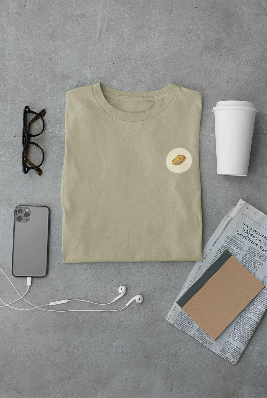 Pastel de Nata T-Shirt in sage green, folded with daily essentials. Organic cotton, minimalist Lisbon style.