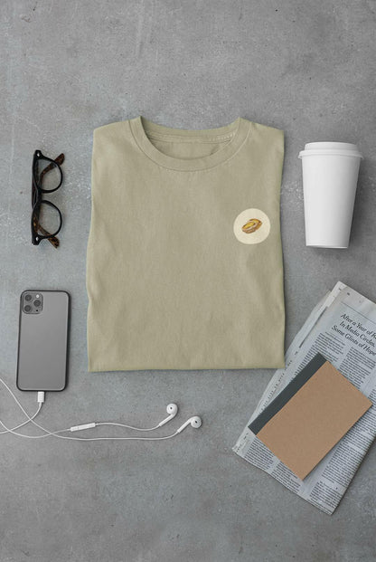 Pastel de Nata T-Shirt in sage green, folded with daily essentials. Organic cotton, minimalist Lisbon style.