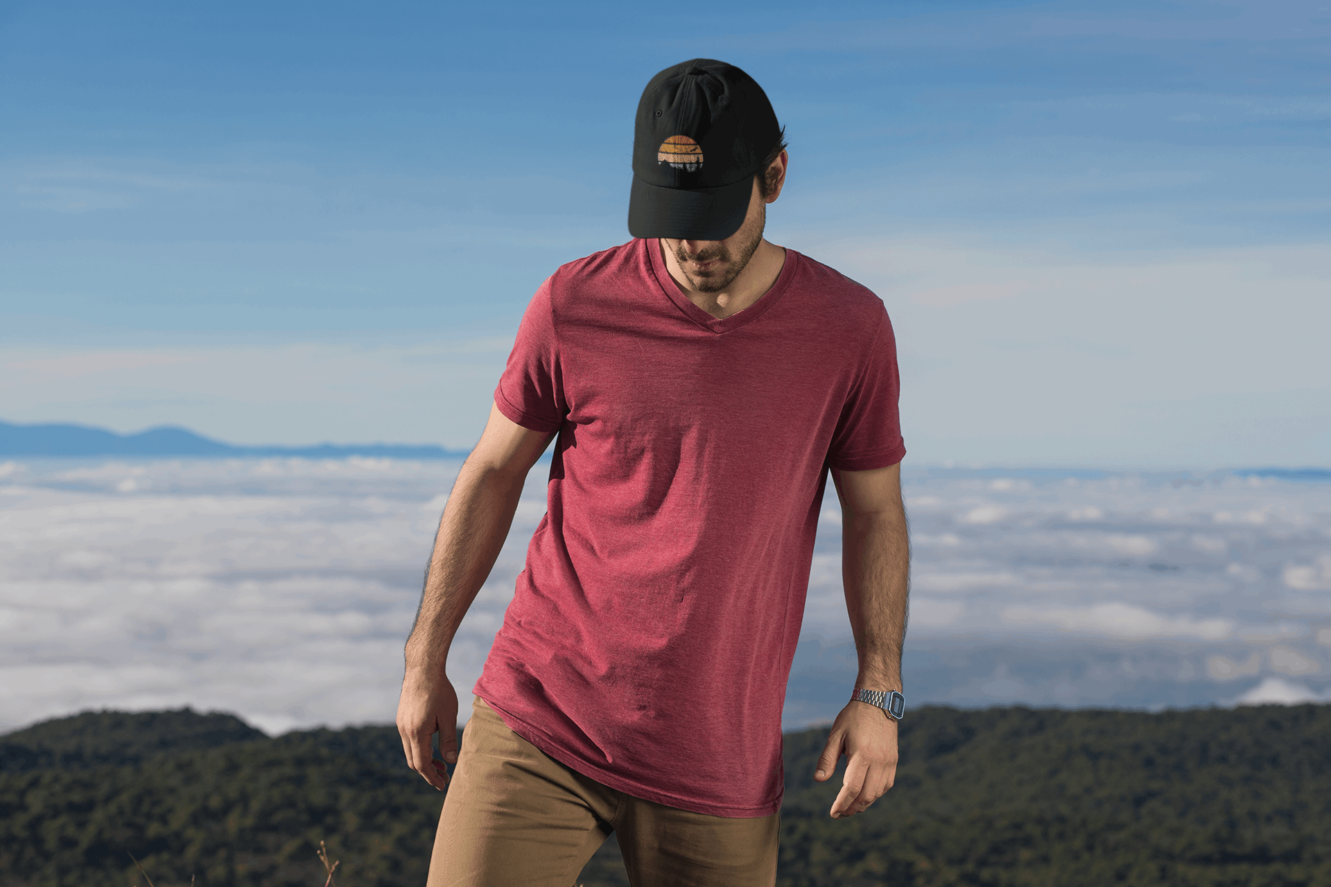 Black Madeira Vintage Cap with a mountain logo, worn by a man standing on a mountain with clouds below. Ideal for adventure seekers.