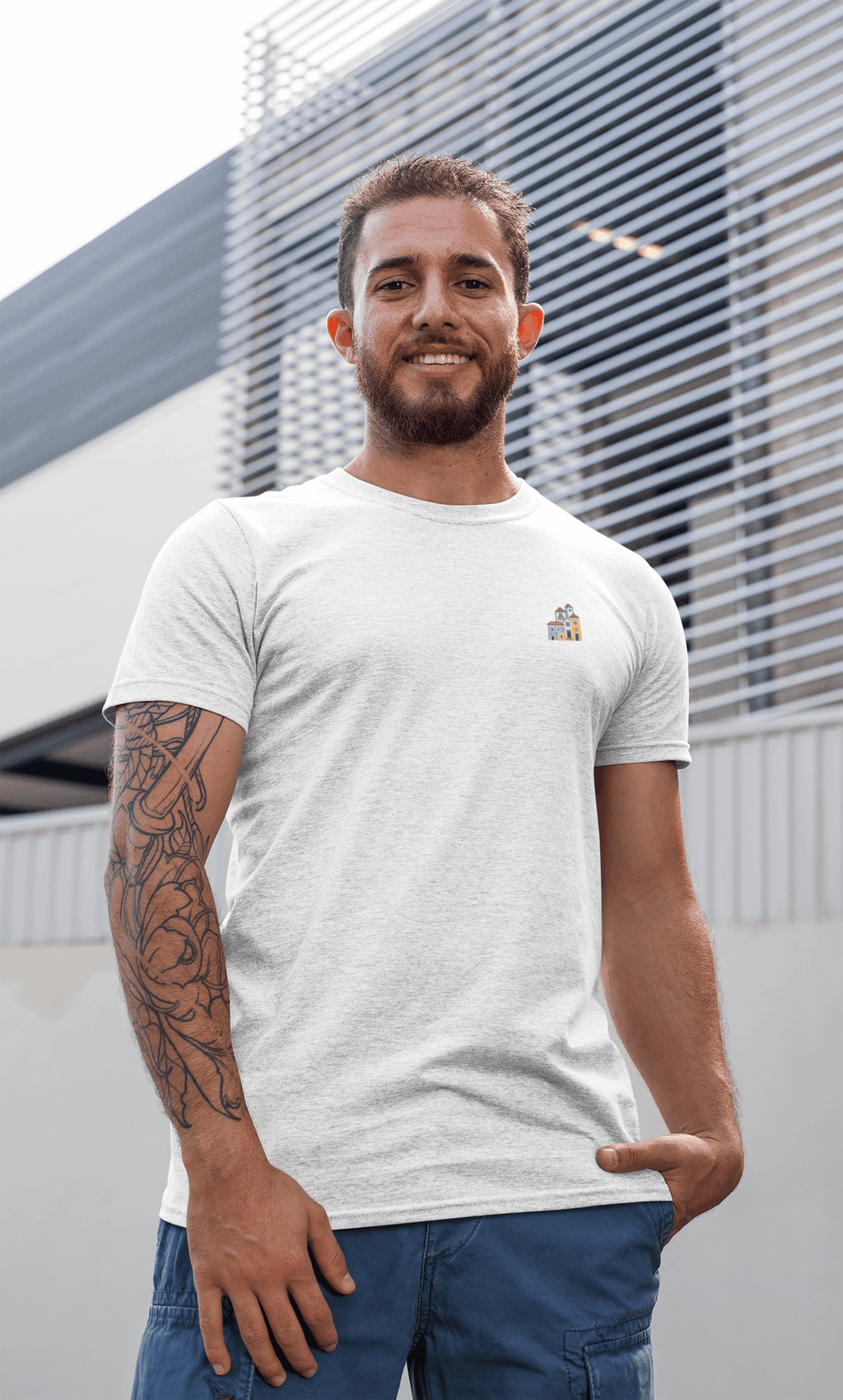 Smiling man wearing a white Minimal Alfama Houses Unisex T-Shirt outdoors, emphasizing its casual fit and sustainable organic cotton material.