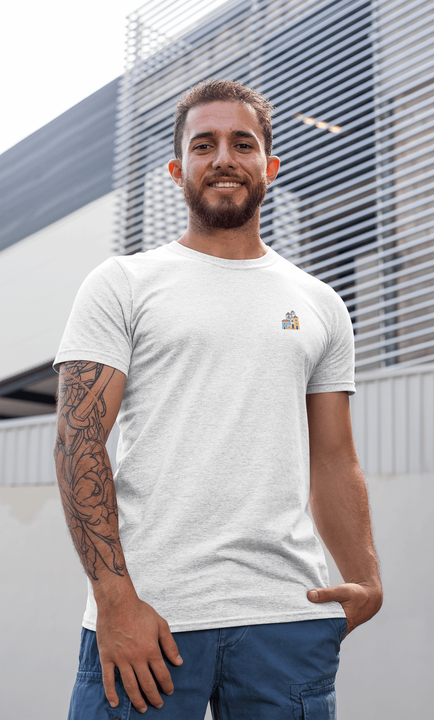 Smiling man wearing a white Minimal Alfama Houses Unisex T-Shirt outdoors, emphasizing its casual fit and sustainable organic cotton material.