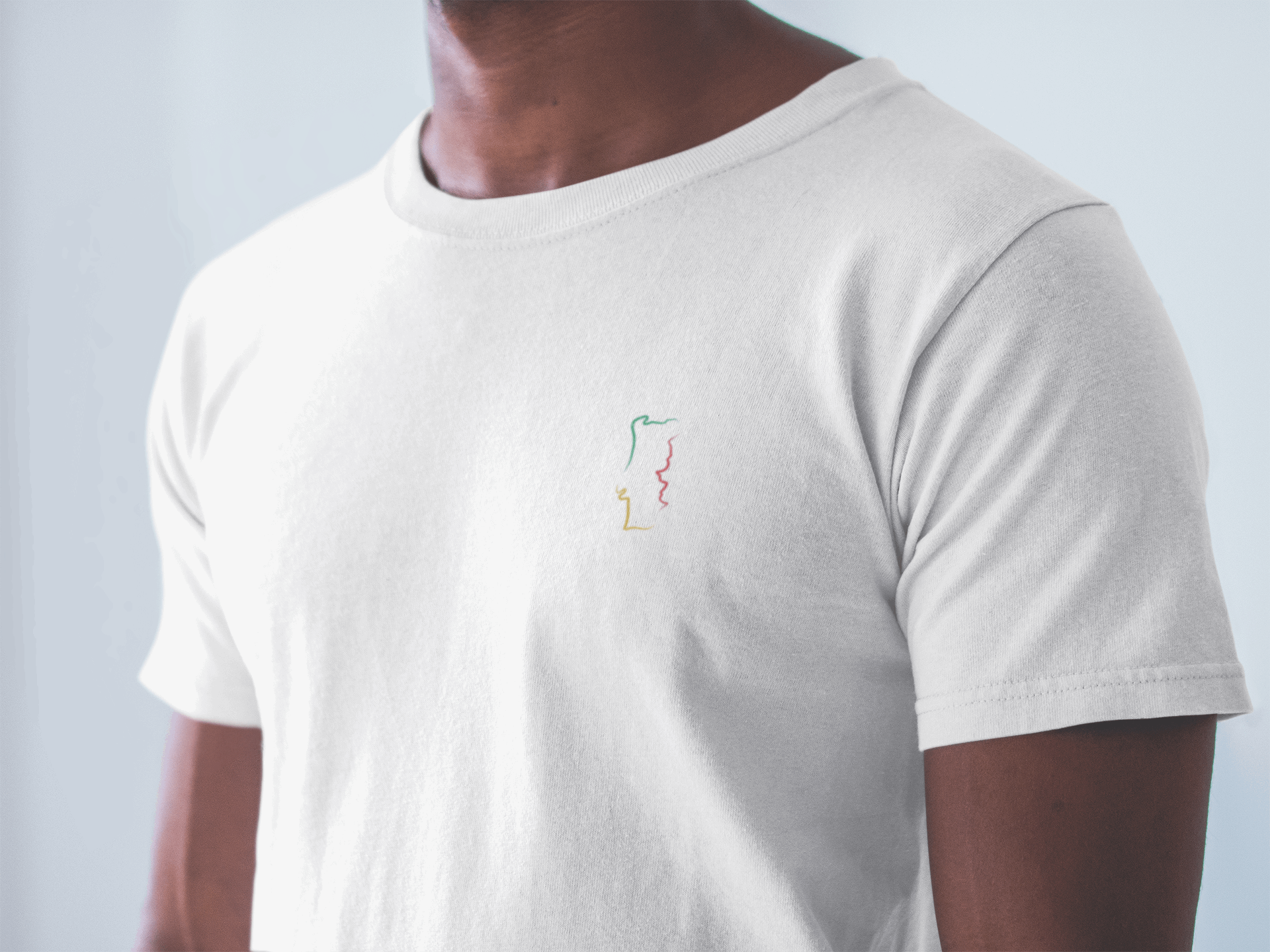 Man in a white Portugal T-Shirt with a minimalist embroidered map design, crafted from GOTS-certified organic cotton for comfort and sustainability.