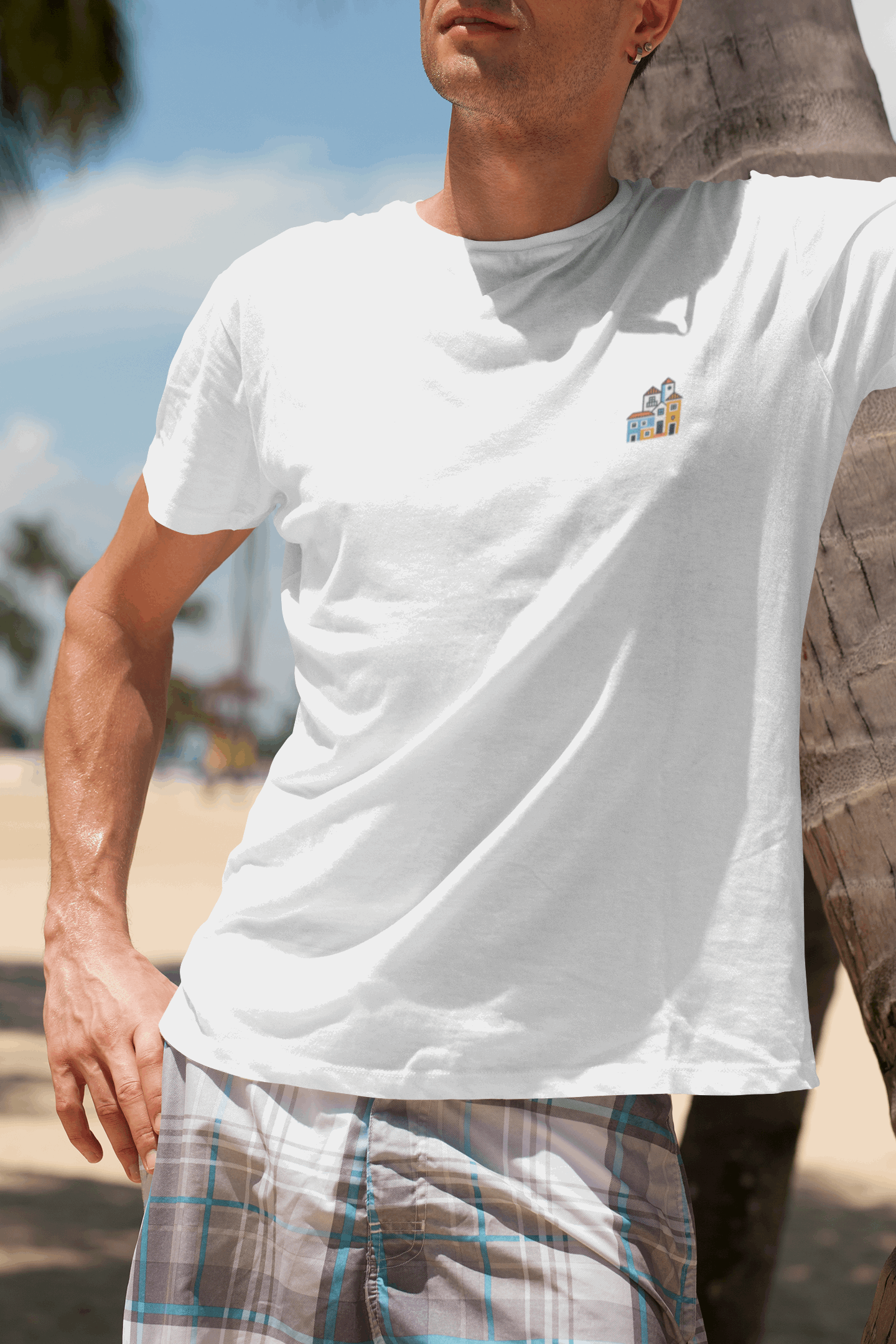 Man wearing a white Minimal Alfama Houses Unisex T-Shirt at the beach, highlighting its breathable organic cotton and stylish minimalist design.