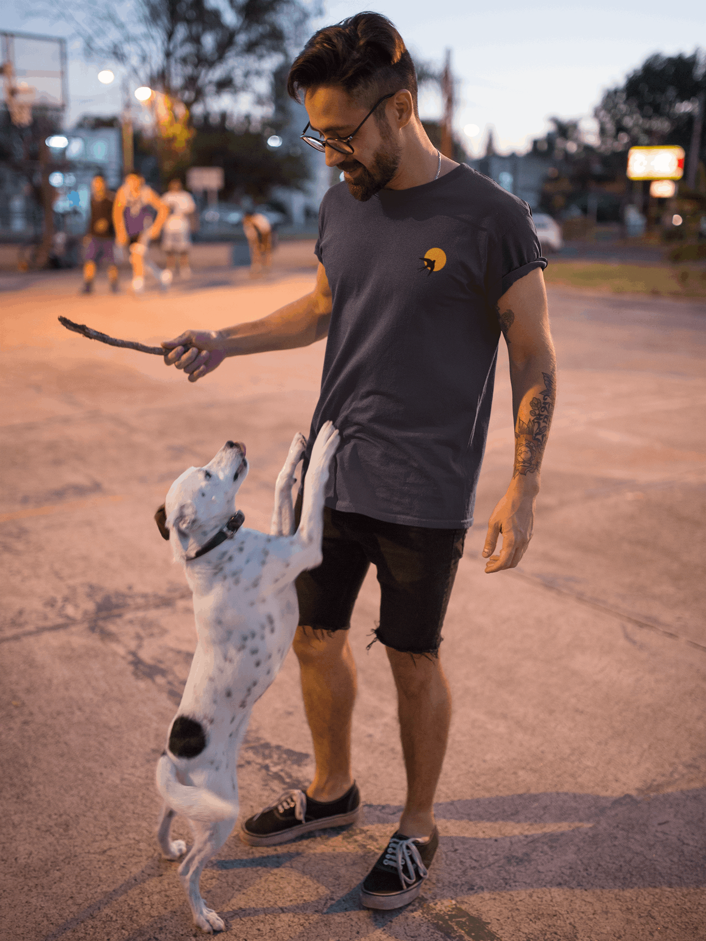 Man wearing a dark grey Andorinha T-Shirt playing with a dog outdoors. A unisex organic cotton tee with a minimalist swallow logo.