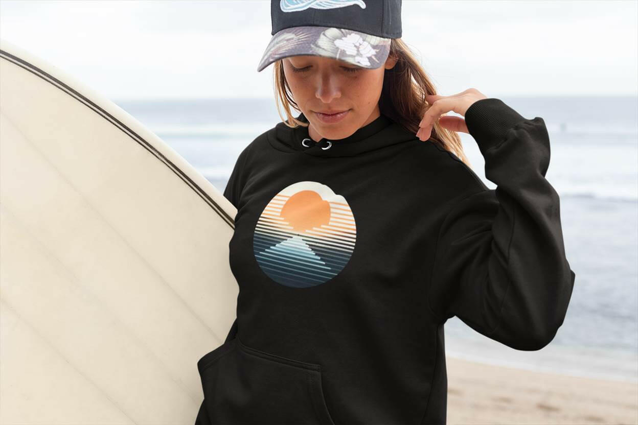 Black Nazaré vintage hoodie with a sunset surf graphic, worn by a woman holding a surfboard. Cozy and sustainable fashion for surf enthusiasts.