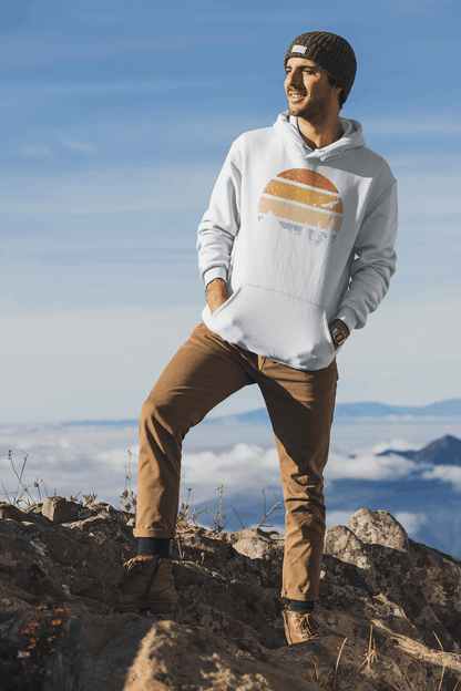 White adventure hoodie with a retro sunset and nature design, worn by a man standing on a rocky peak with a scenic backdrop.