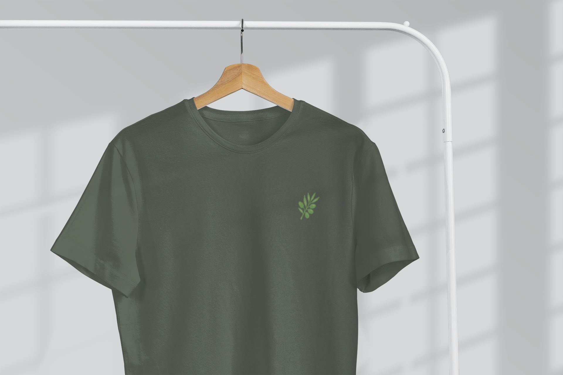 Green t-shirt with a small logo on a hanger against a gray background