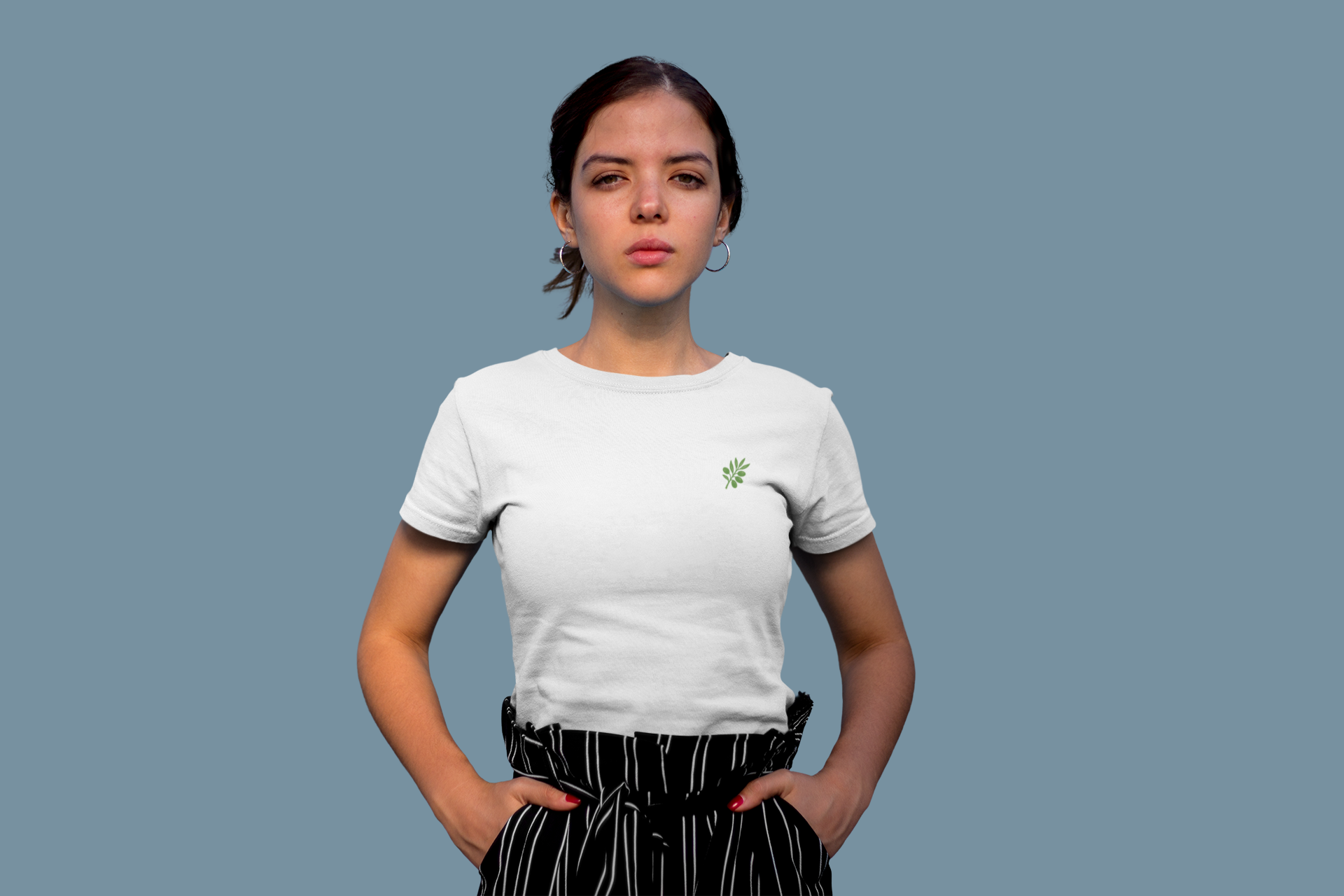 Person wearing a white t-shirt with a small green logo on a plain background