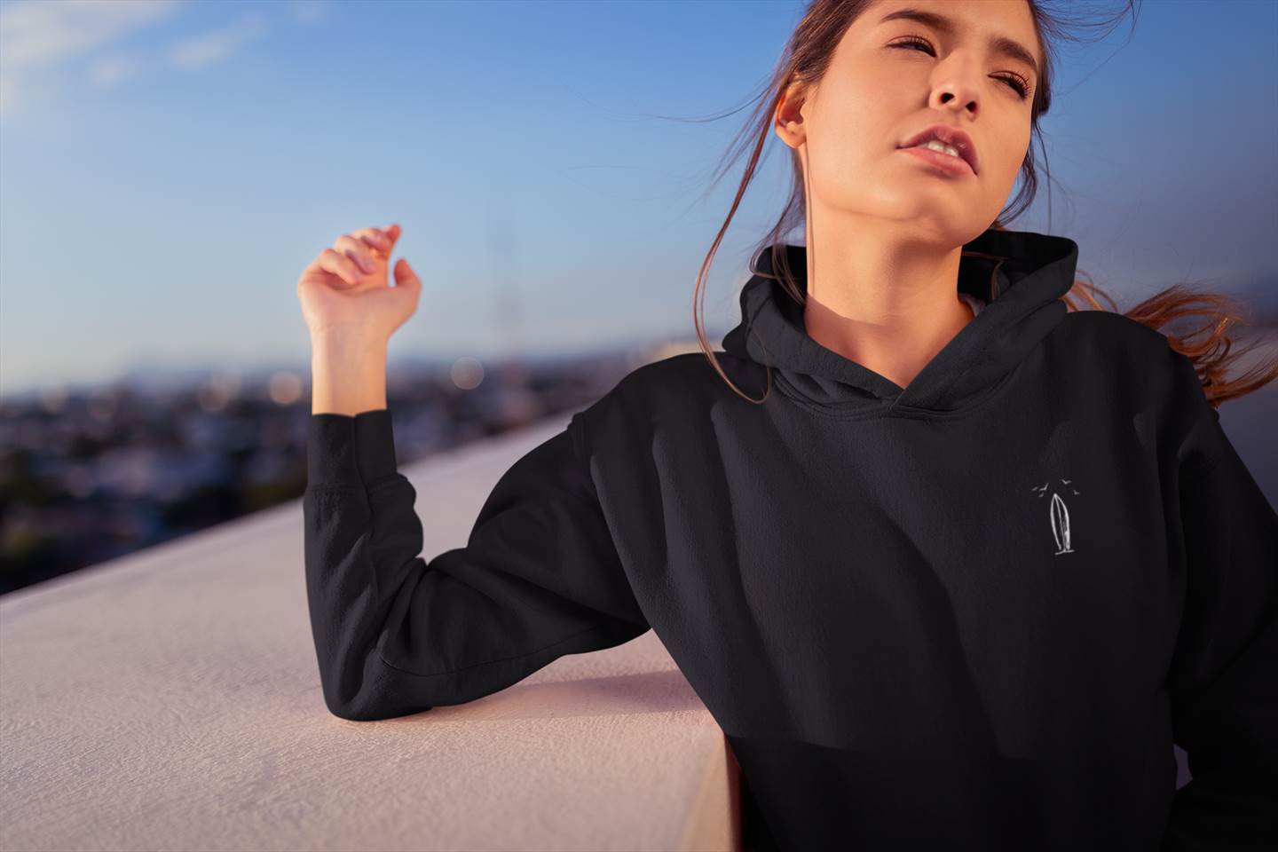 Black Ericeira Surf Hoodie styled on a rooftop with city views. A sustainable and stylish hoodie for urban and surf culture lovers.