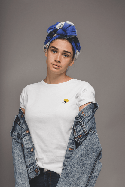 White Andorinha T-Shirt with a small swallow and sun logo, styled with a denim jacket. A unisex organic cotton tee celebrating Portuguese heritage.