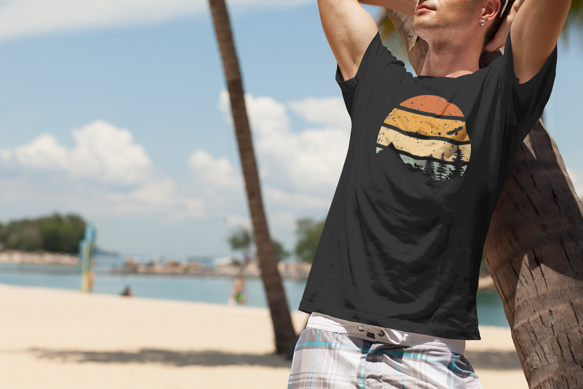 Man on the beach wearing a black Madeira Mountains Retro Organic Vintage T-Shirt. A stylish and breathable hiking tee for summer.