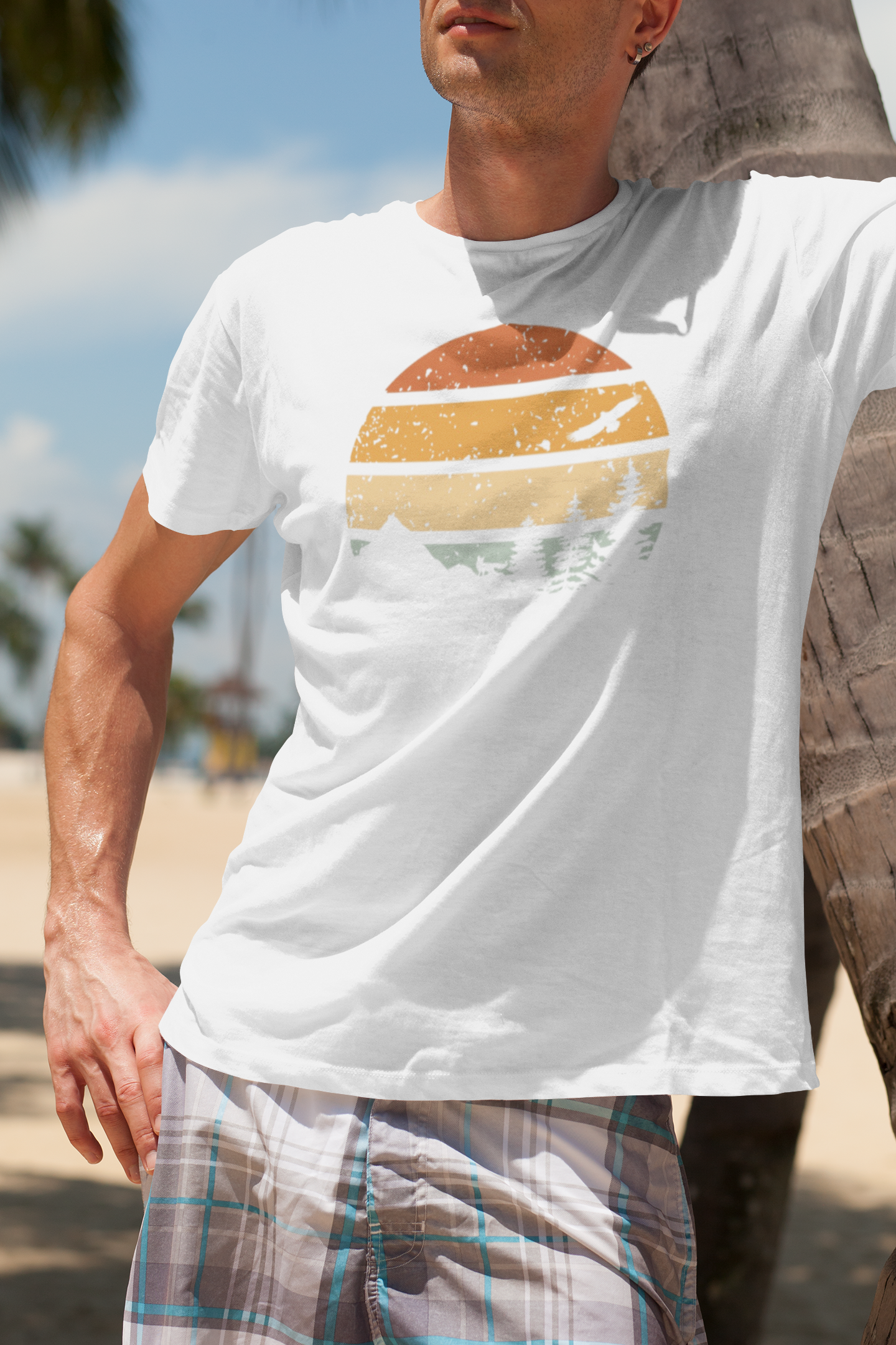 Man leaning against a palm tree in a white Madeira Mountains Retro Organic Vintage T-Shirt. A lightweight and stylish hiking tee.