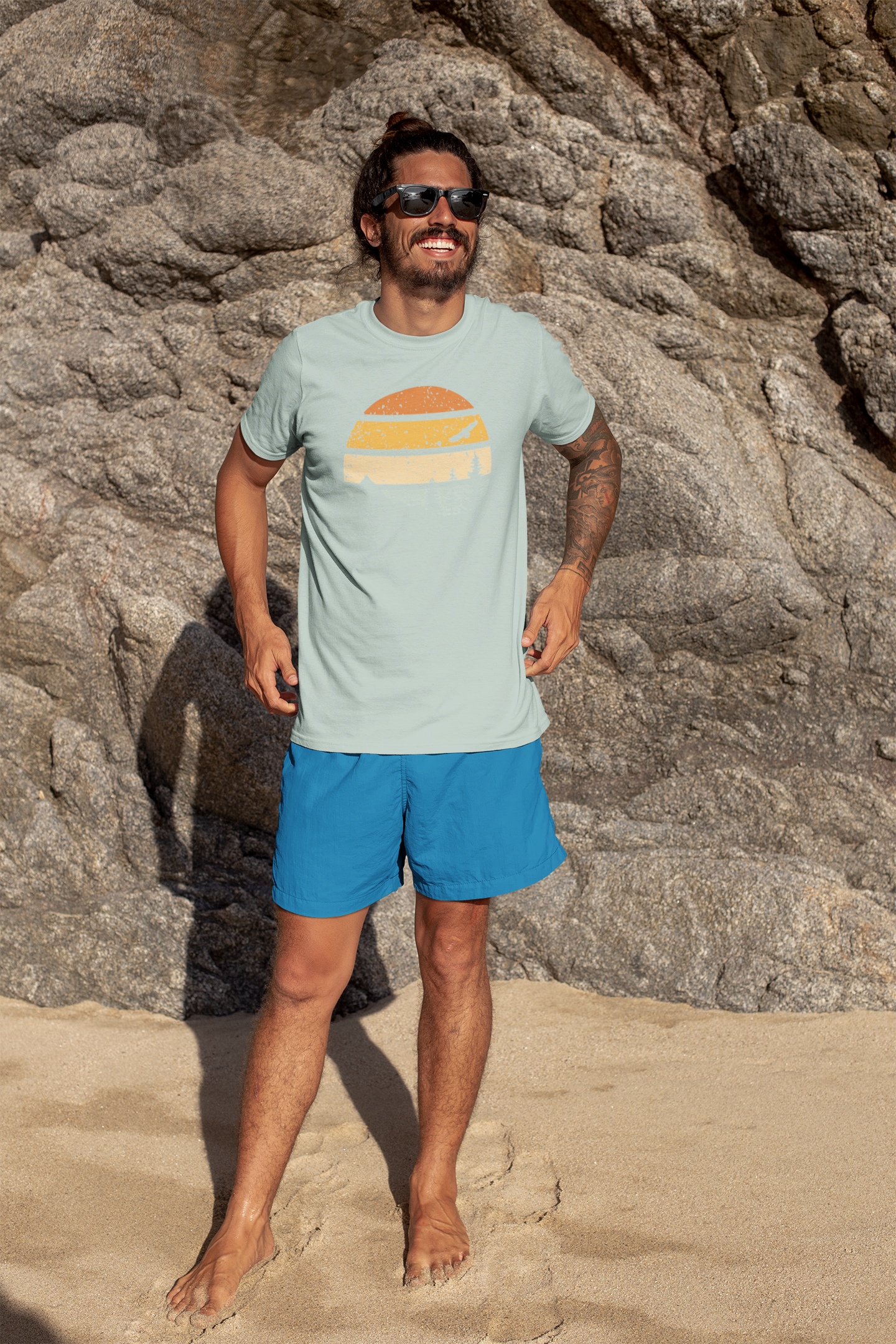 Man on the beach wearing a light green Madeira Mountains Retro Organic Vintage T-Shirt. A breathable and stylish hiking tee for summer.
