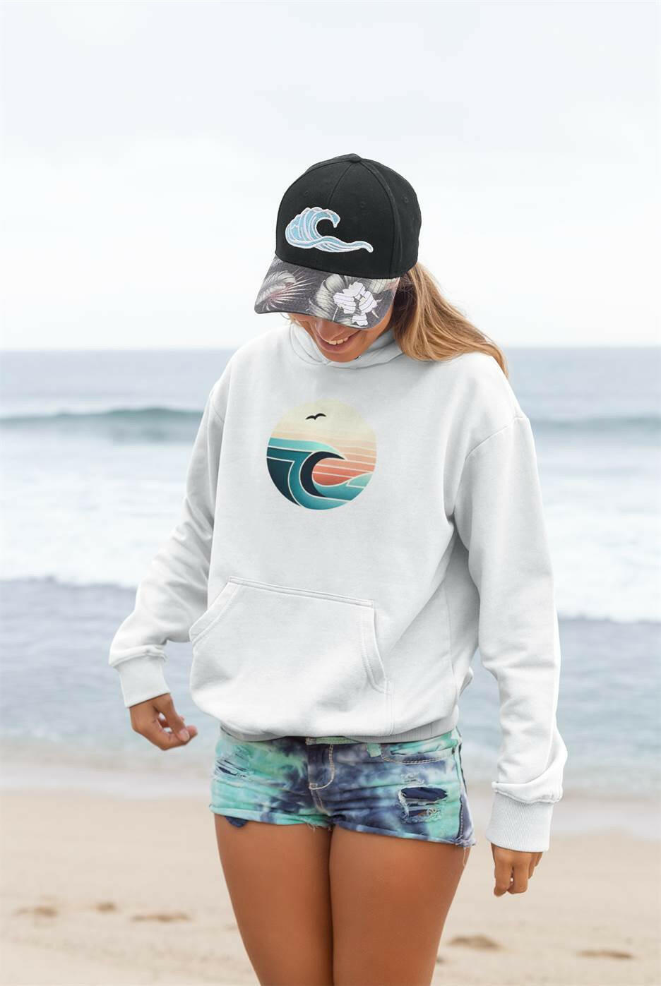 White Nazaré Surf Wave Hoodie paired with a surf cap. Stylish and sustainable unisex hoodie with a vintage surf aesthetic.