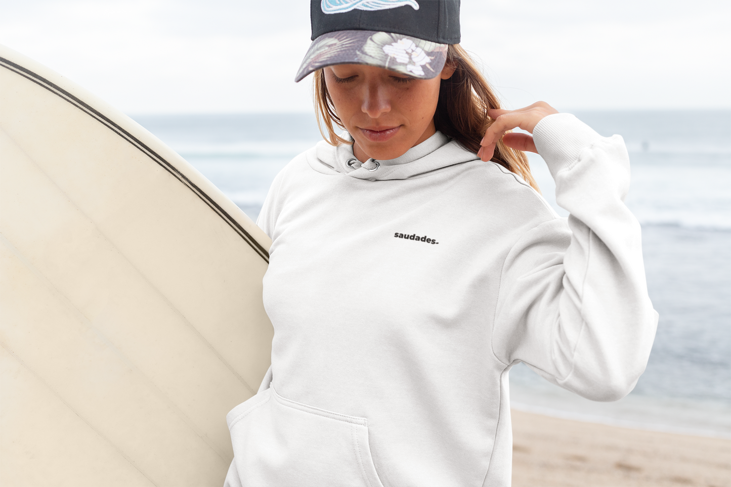 Unisex Saudade hoodie displayed in a coastal lifestyle setting