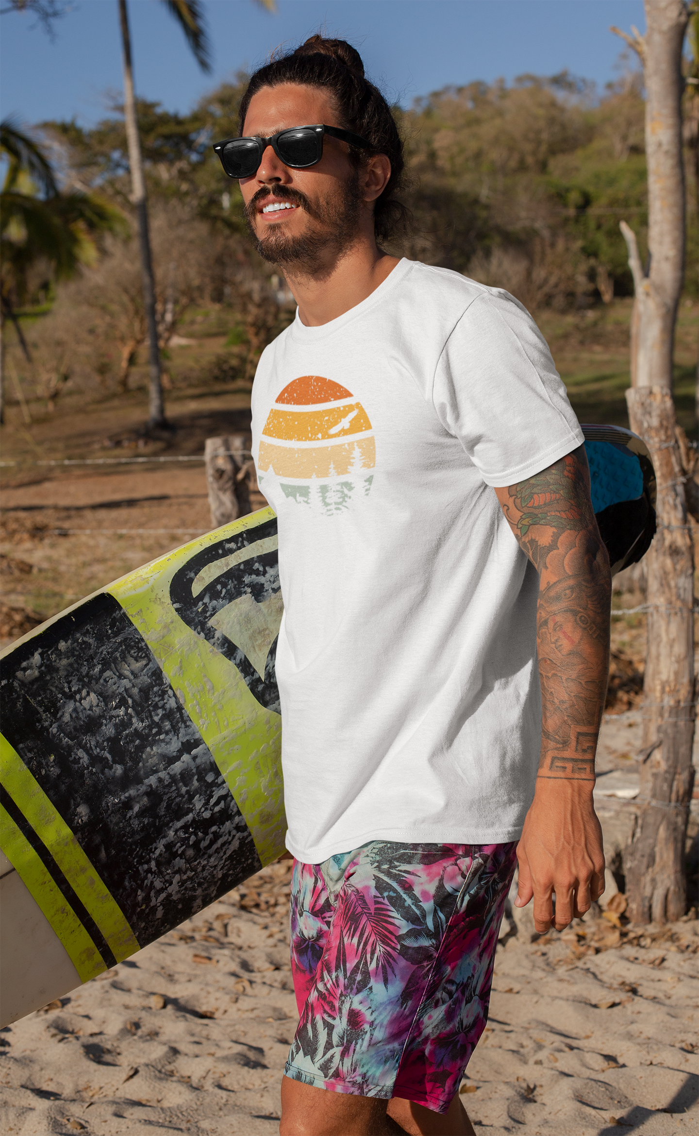 Man with a surfboard wearing a white Madeira Mountains Retro Organic Vintage T-Shirt. A lightweight hiking tee for beach lovers.