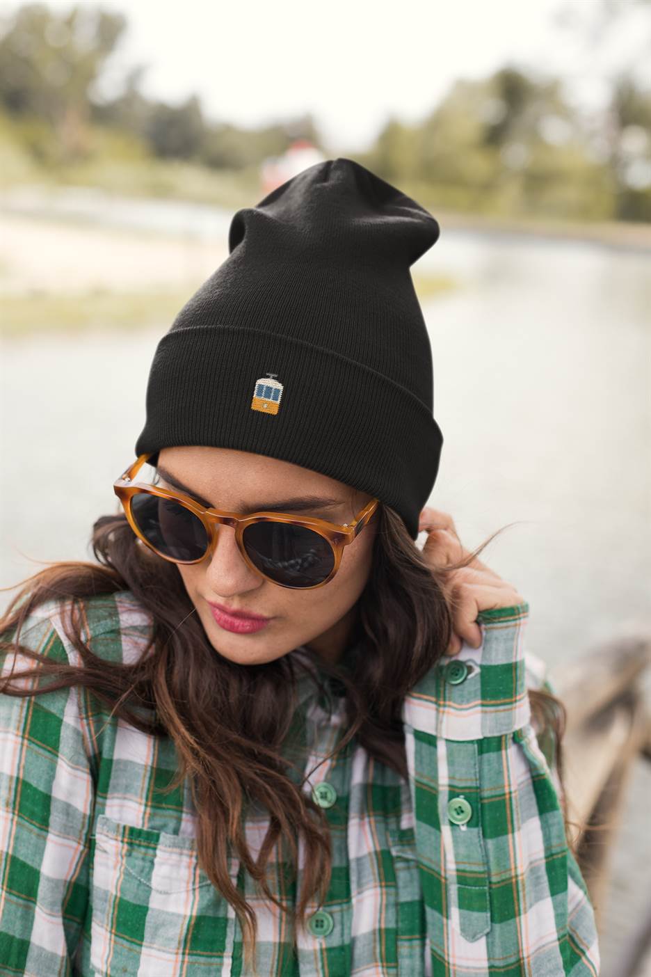 Black Lisbon Electrico Beanie worn with sunglasses and a plaid shirt. A trendy unisex embroidered hat inspired by Lisbon's iconic tram.