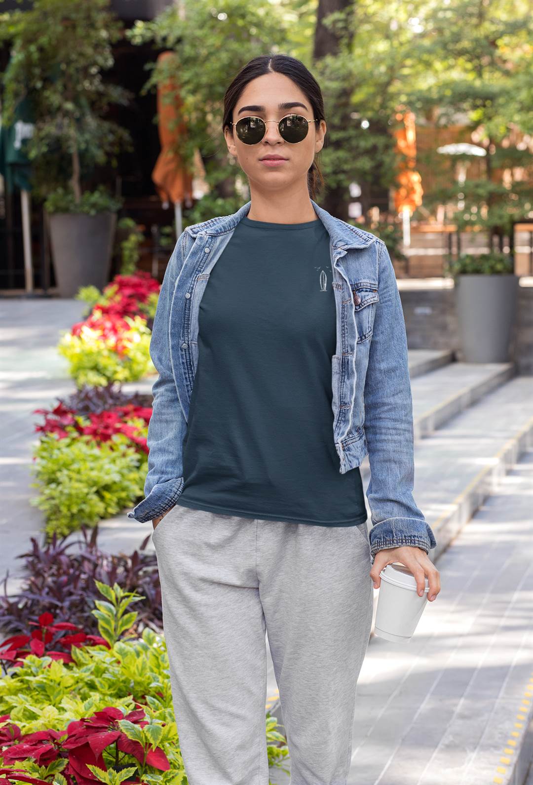 Dark green Ericeira Surf Organic T-Shirt for women, featuring a minimalist surfboard design, paired with a denim jacket and joggers for a relaxed street style.
