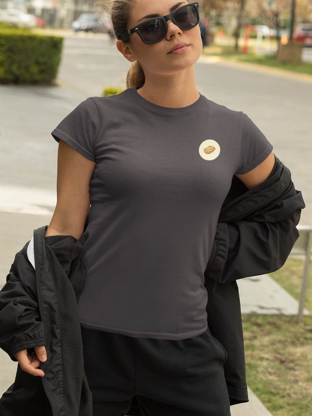 Charcoal gray Lisbon Style T-Shirt for women with a small Pastel de Nata emblem. Organic cotton tee styled with a sporty black jacket and sunglasses.