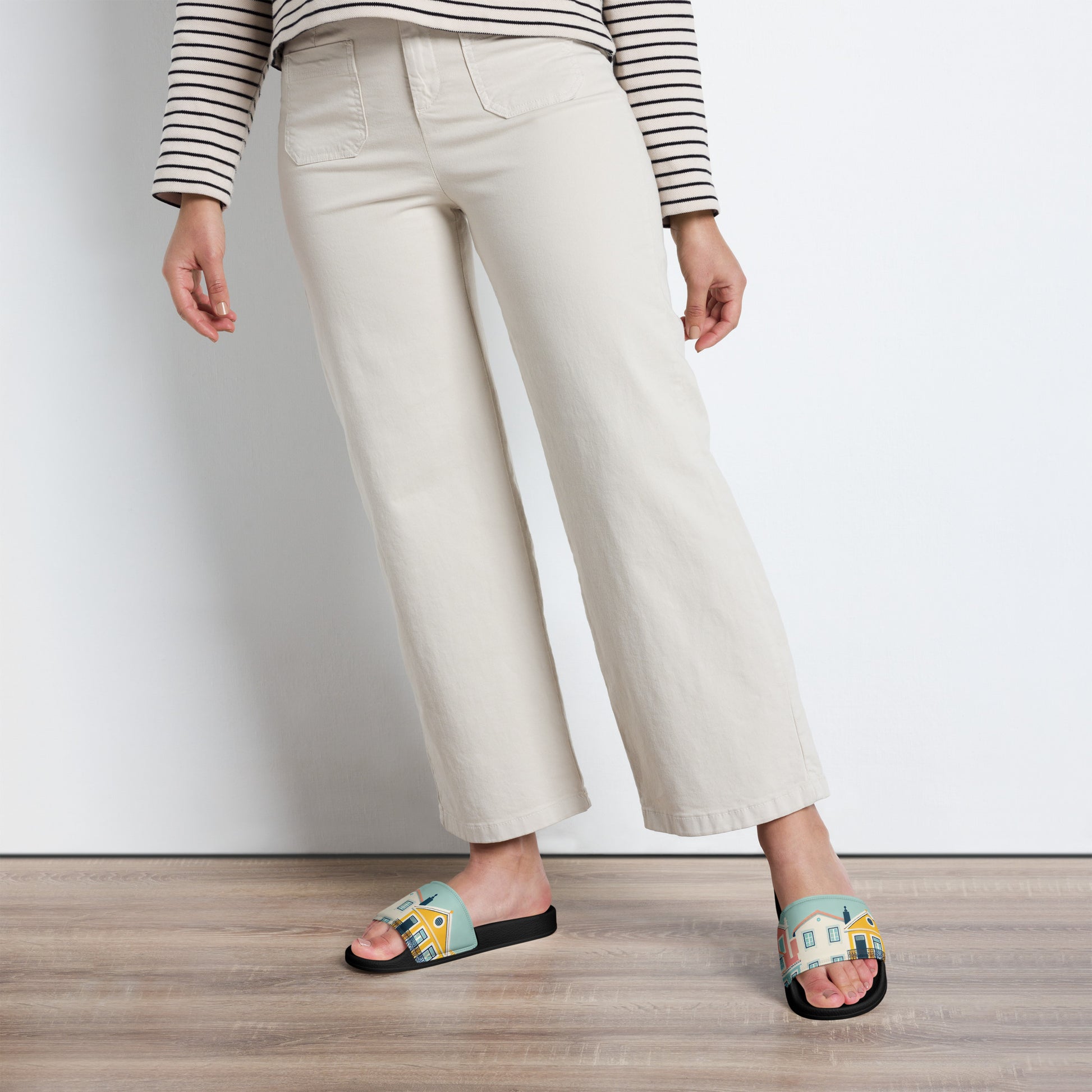 Model wearing Alfama Woman Pool Slippers with a Lisbon-inspired design, paired with cream-colored pants. A stylish and comfortable footwear choice.