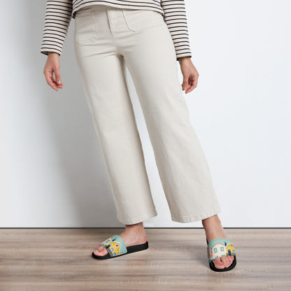 Model wearing Alfama Woman Pool Slippers with a Lisbon-inspired design, paired with cream-colored pants. A stylish and comfortable footwear choice.